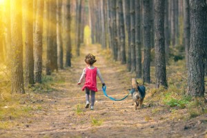 Cchild walking at the forest with her dog