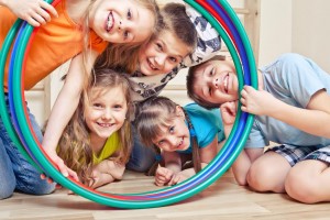 Five cheerful kids looking through hula hoops